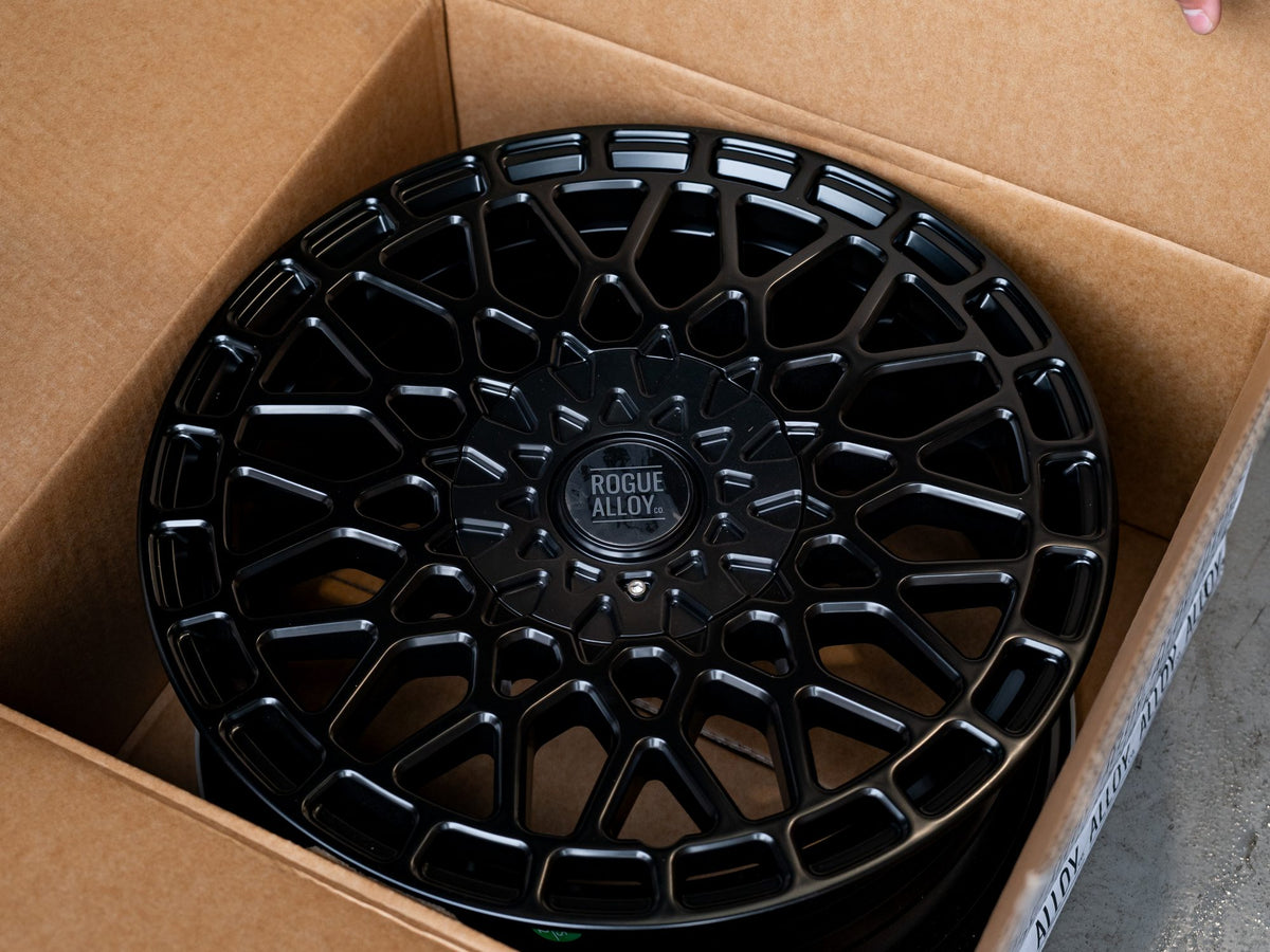 Opening a Rogue Alloy box to find a black mesh wheel inside
