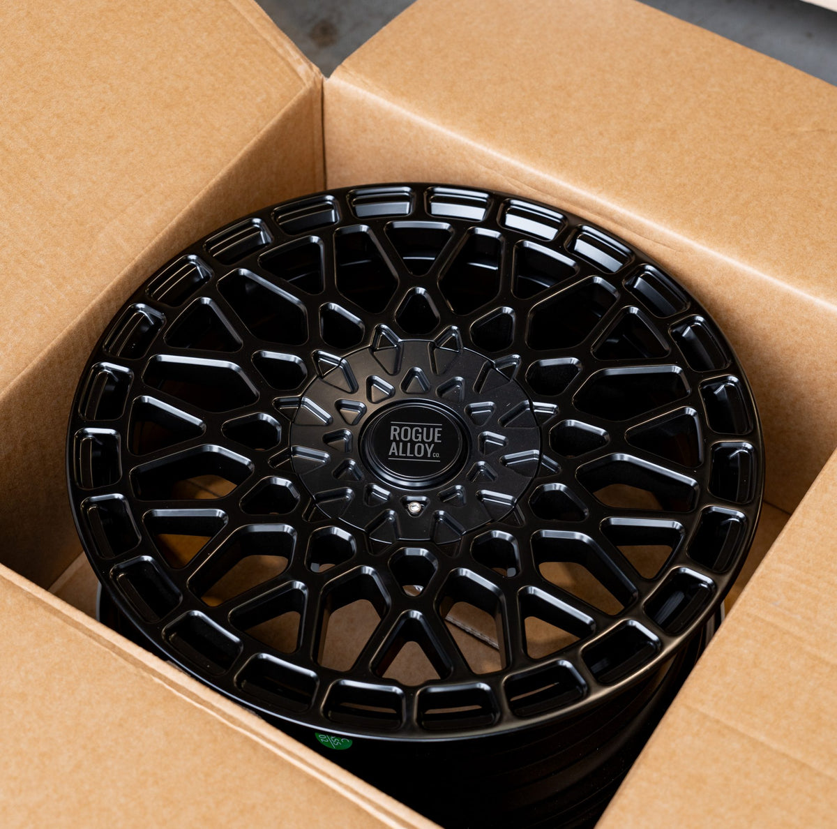 A black mesh Rogue wheel packed in its own cardboard box, ready for the pallet