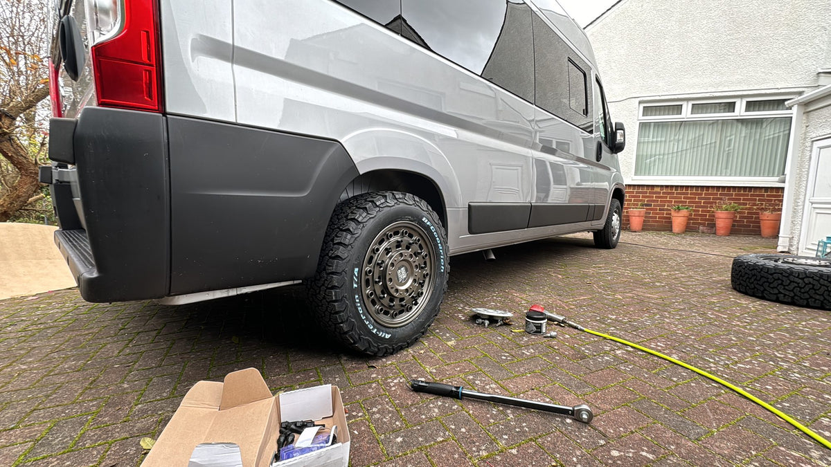 A new set of Rogue wheels going onto a Ducato-based van on a driveway, the torque bar and fitting kit laid out