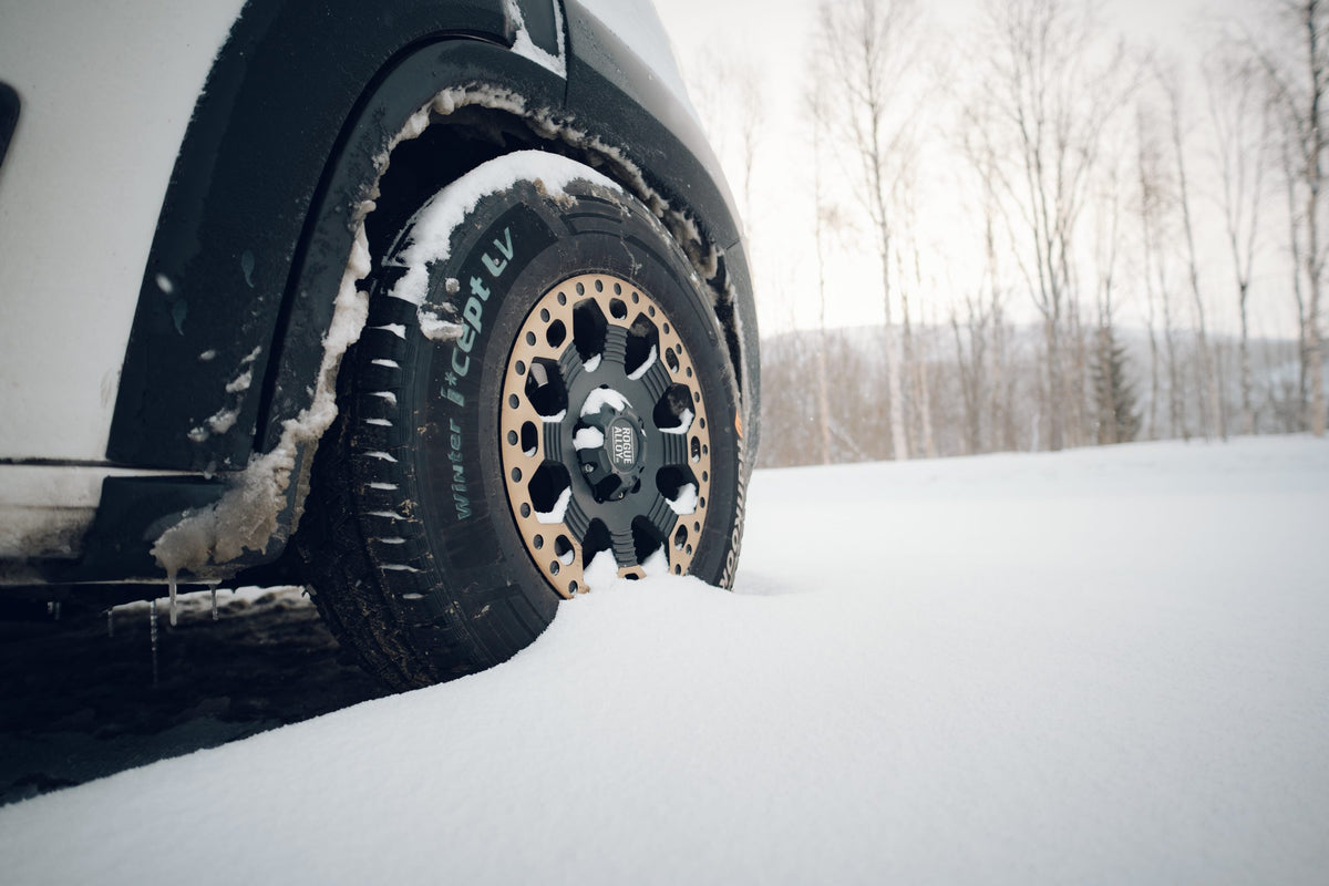 A Rogue wheel and all-terrain tyre in deep snow beside birch trees