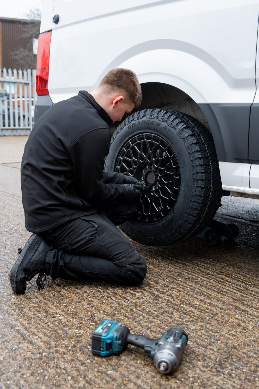 A Rogue fitter fitting a black mesh Rogue wheel to a Volkswagen Crafter on a trolley jack in the Rogue yard