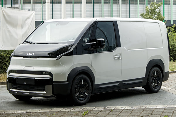 Front three-quarter view of a Kia PV5 Cargo on factory wheels, photographed in 2026
